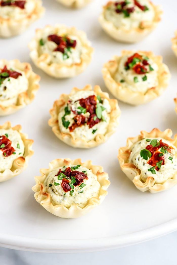 shells filled with tomato pesto, easy appetizers finger foods, arranged on white plate, sun dried tomatoes and parsley on top