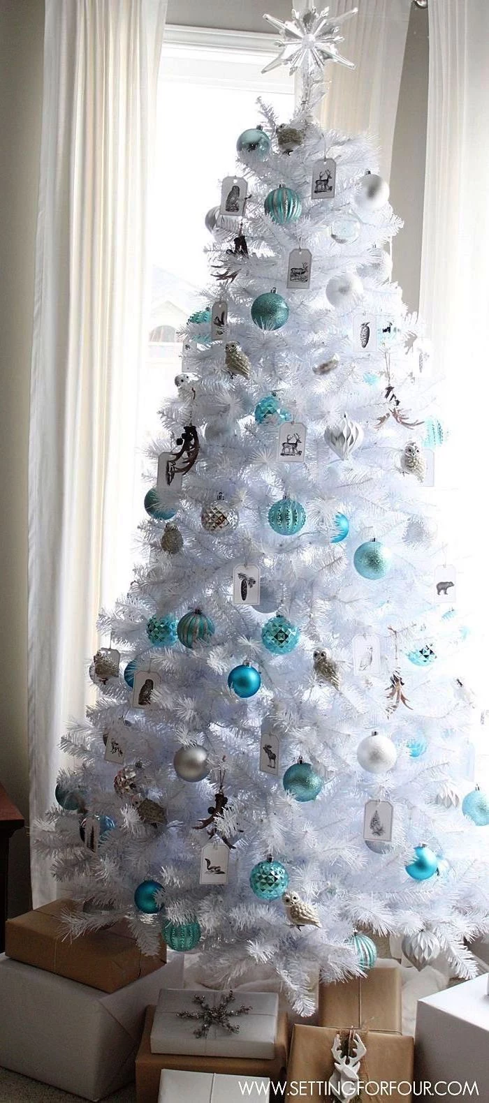 how to decorate a christmas tree with ribbon, white faux tree, silver and turquoise ornaments, wrapped presents underneath
