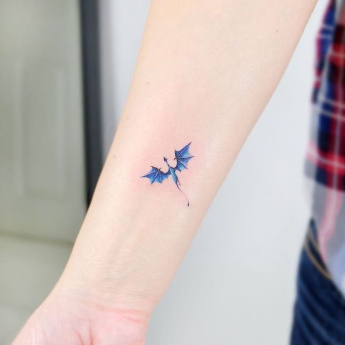 small blue dragon flying, forearm tattoo, dragon tattoos for women, blurred background