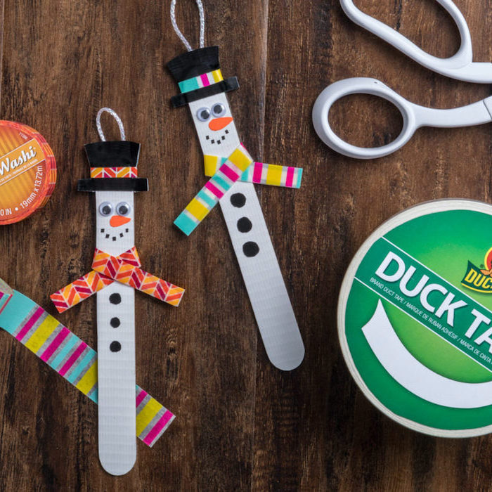 popsicle sitcks snowmen, scarfs made with colorful washi tape, diy ornaments for kids, placed on wooden surface
