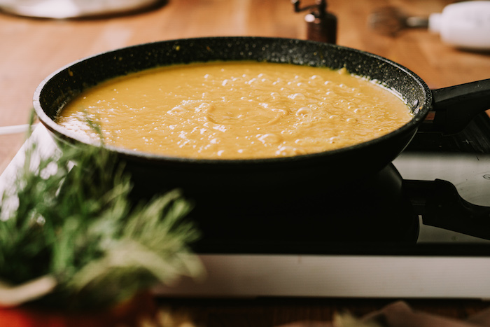 pumpkin puree cooking in a black skillet, potato soup recipe, hot plate placed on a wooden tabel
