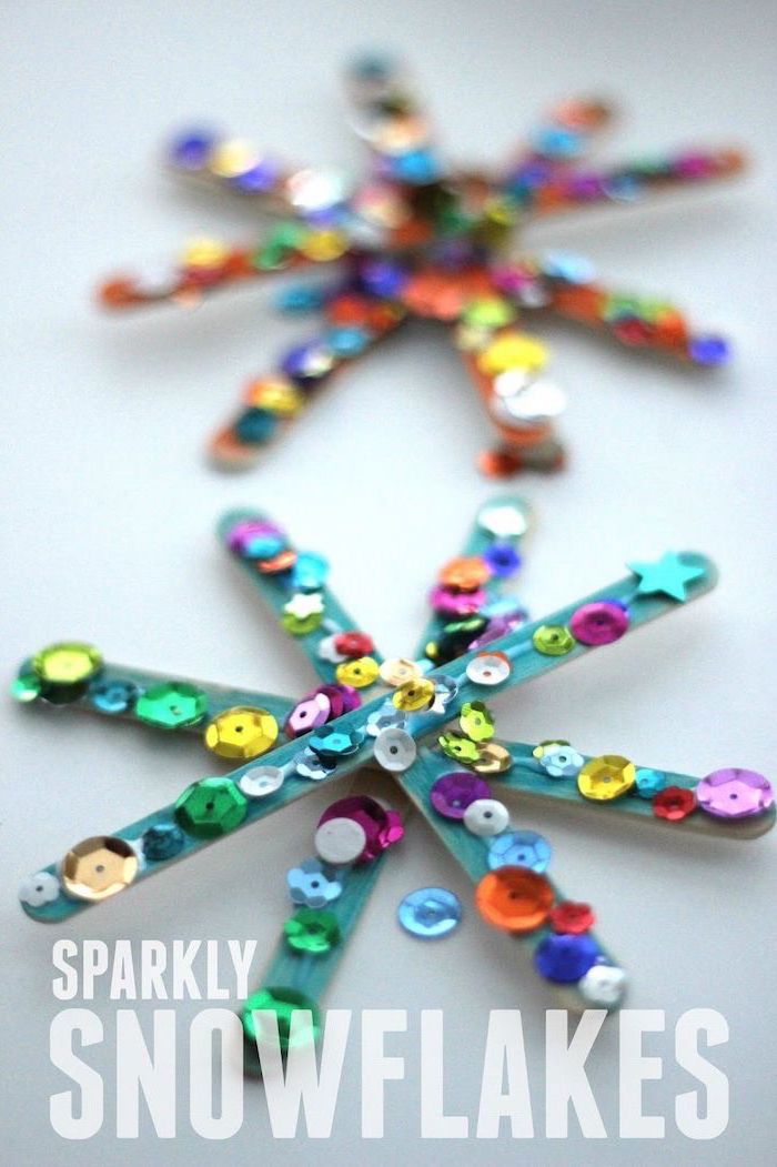 popsicle sticks painted blue, in the shape of snowflakes, diy ornaments for kids, colorful beads glued to them