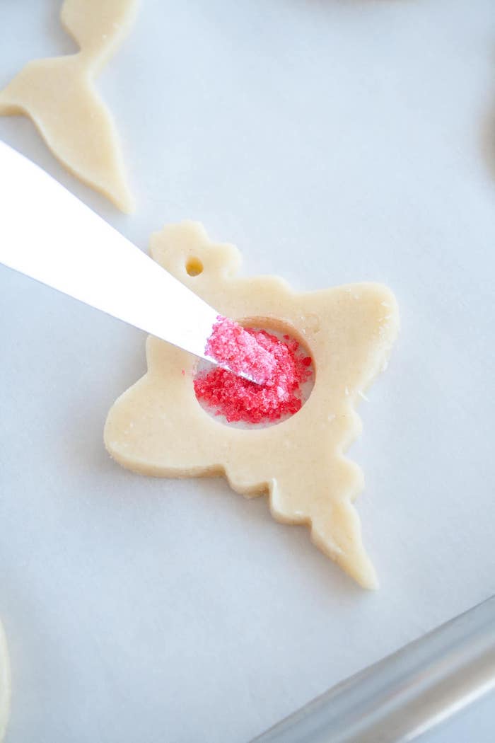 how to make stained glass cookies, sugar cookie icing recipe, pink sugar poured on the dough, placed on paper lined tray