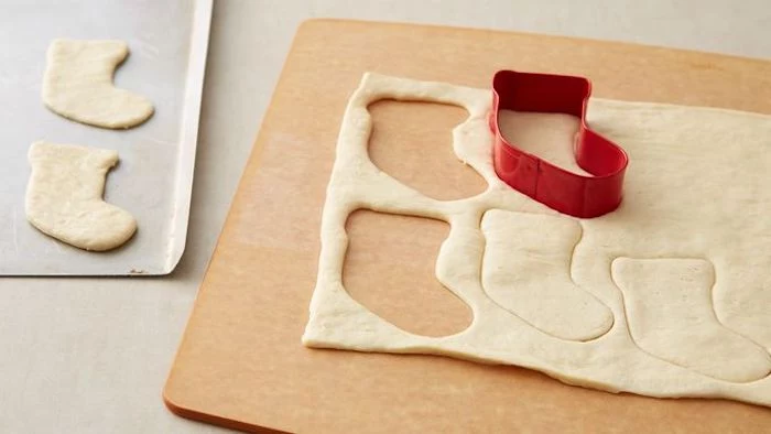 stocking shaped cookie cutter, used on dough, placed on wooden board, holiday appetizers, placed on white surface