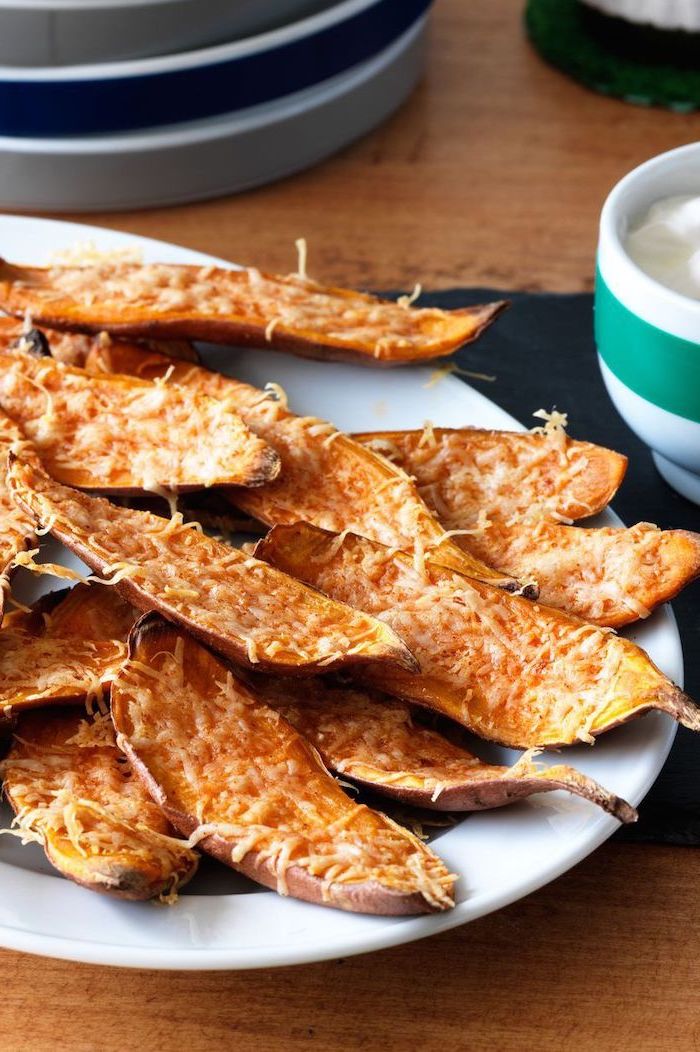 baked sweet potato skins with cheese on top, placed on white plate, christmas eve appetizers, placed on wooden surface