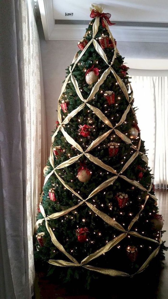 gold ribbon arranged on a tree, how to decorate a christmas tree with ribbon, gold and red ornaments and presents