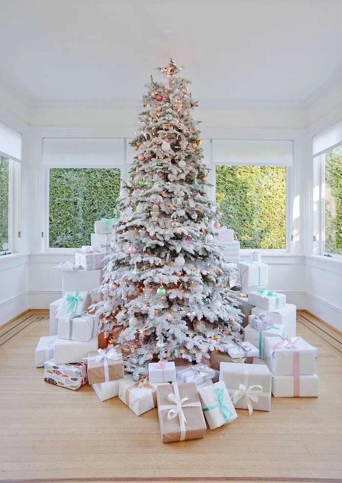 tall tree with faux snow, surrounded by presents, white christmas tree decor, decorated with small ornaments