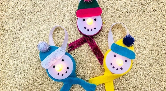 how to make ornaments, tea light snowmen, scarfs and beanies made of felt, placed on gold glittery surface