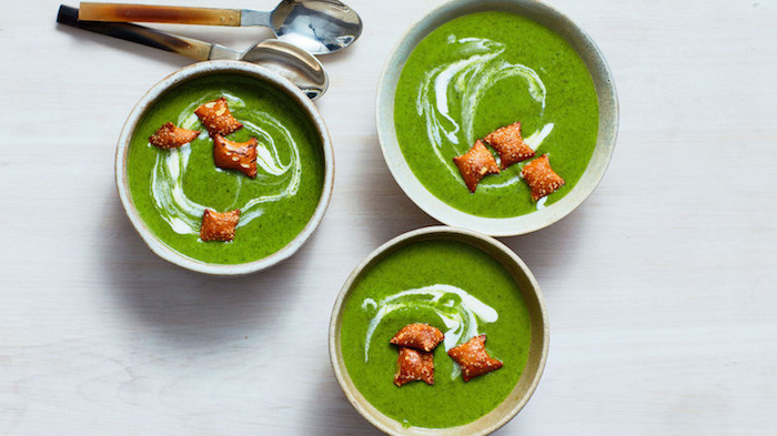 three ceramic bowls full of soup, two spoons on the side, white wooden table, homemade cream of chicken soup