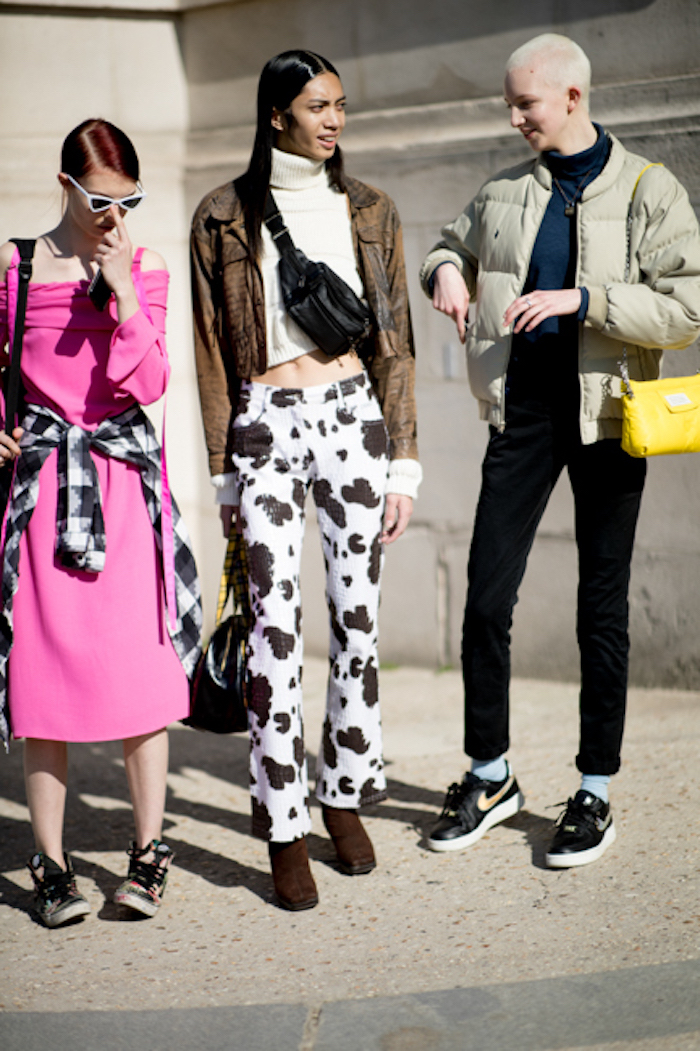 three women standing on a sidewalk, dressed in different outfits, 2019 style trends, casual style with sneakers and boots