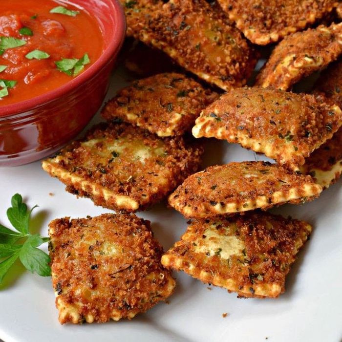 toasted ravioli on white plate, easy appetizers finger foods, ceramic bowl full of tomato sauce, parsley garnish on top
