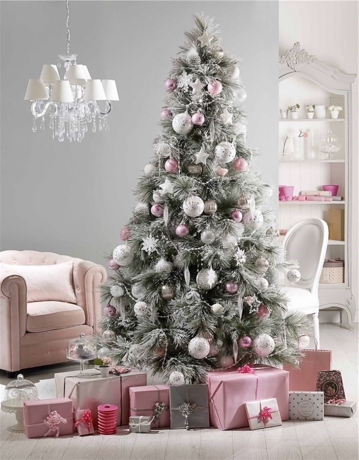 tree with faux snow, decorated with pink and silver ornaments, white christmas tree decor, wrapped presents underneath