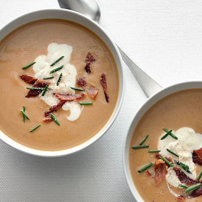 two white bowls, full of cream soup, bacon garnish on top, cream of mushroom soup recipe, white table cloth