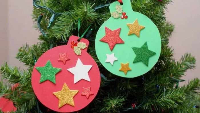 baubles made of red and green paper, colorful glittery stars glued to them, how to make ornaments, hanging on tree with lights
