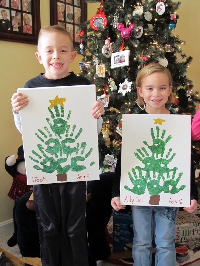 two kids holding canvases, christmas trees made with their handprints, christmas crafts for toddlers age 2 3