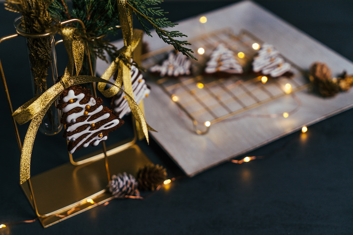 christmas tree shaped cookies, hanging with golden ribbon, vegan gingerbread cookies, lights around them