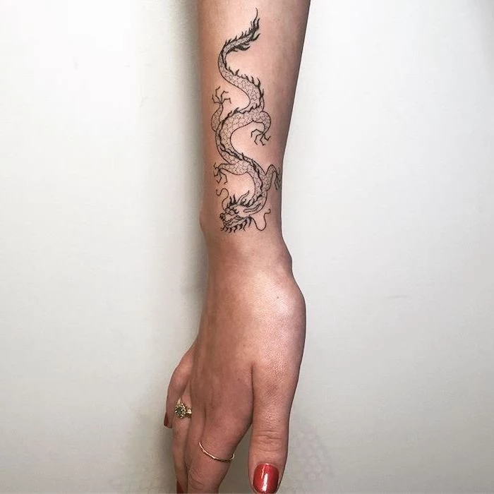 wrist tattoo, woman with red nail polish, dragon tattoo design, white background