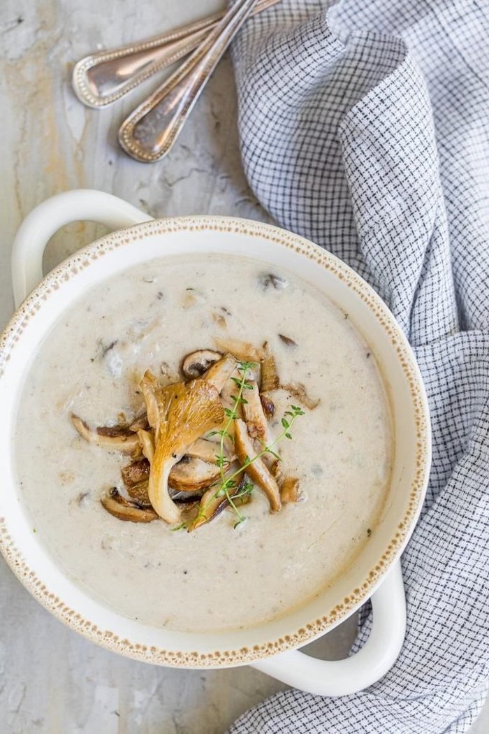 homemade cream of mushroom soup, white ceramic bowl full of soup, mushrooms on top, white table cloth on the side