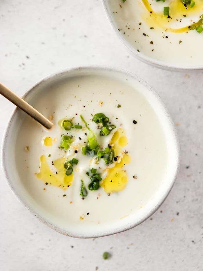 two white ceramic bowls full of soup, chopped green onions on top for garnish, homemade cream of mushroom soup