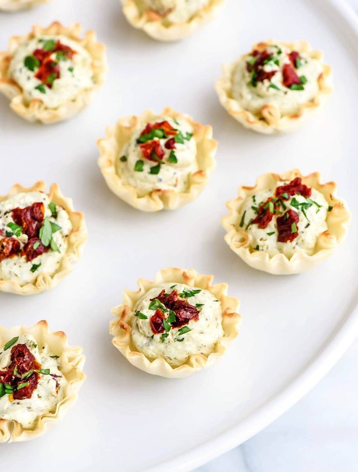 tomato pesto bites, easy party snacks, sun dried tomatoes and parsley garnish, arranged on white plate
