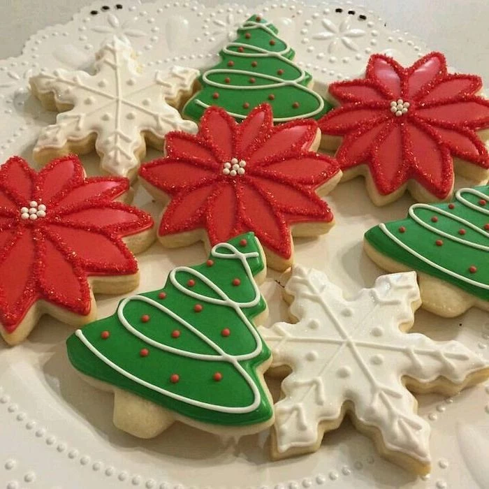 cookies in the shape of christmas trees, snowflakes and flowers, decorated with white green and red icing, royal icing recipe for sugar cookies