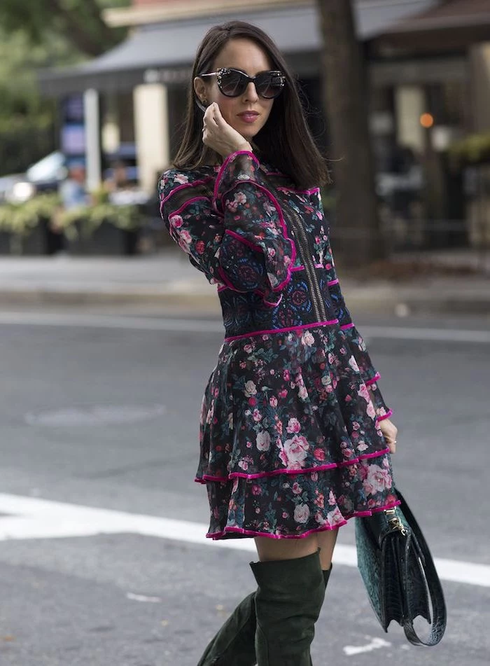woman walking down the street, wearing a dress with floral motifs, knee high boots and sunglasses, fashion trends