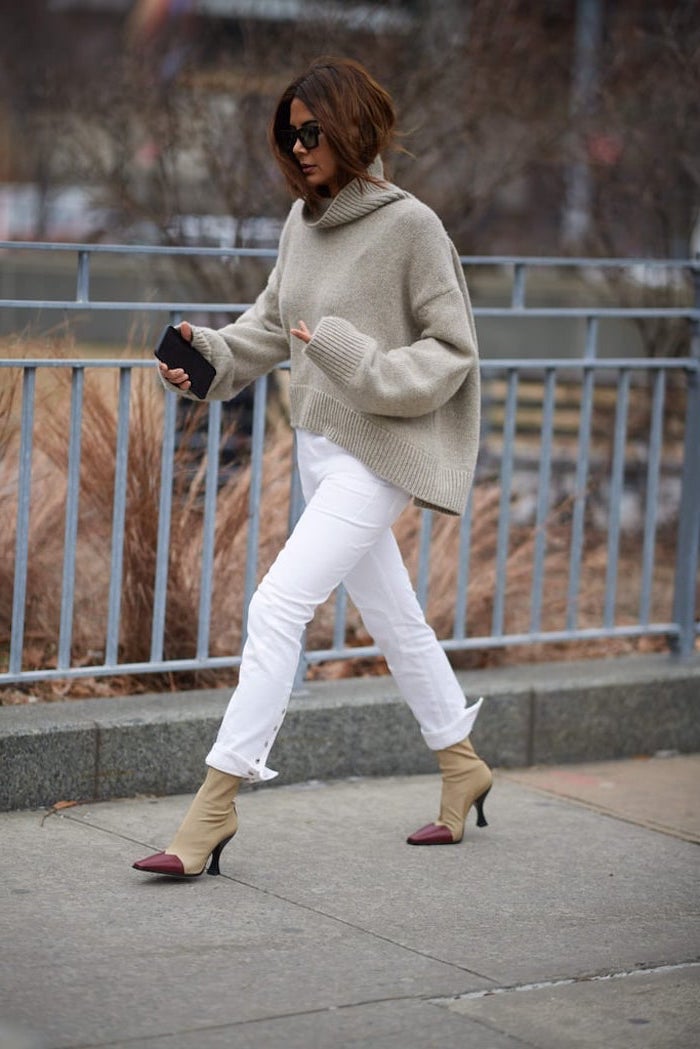 woman walking down the street, wearing white pants and oversized sweater, new york winter fashion, beige boots