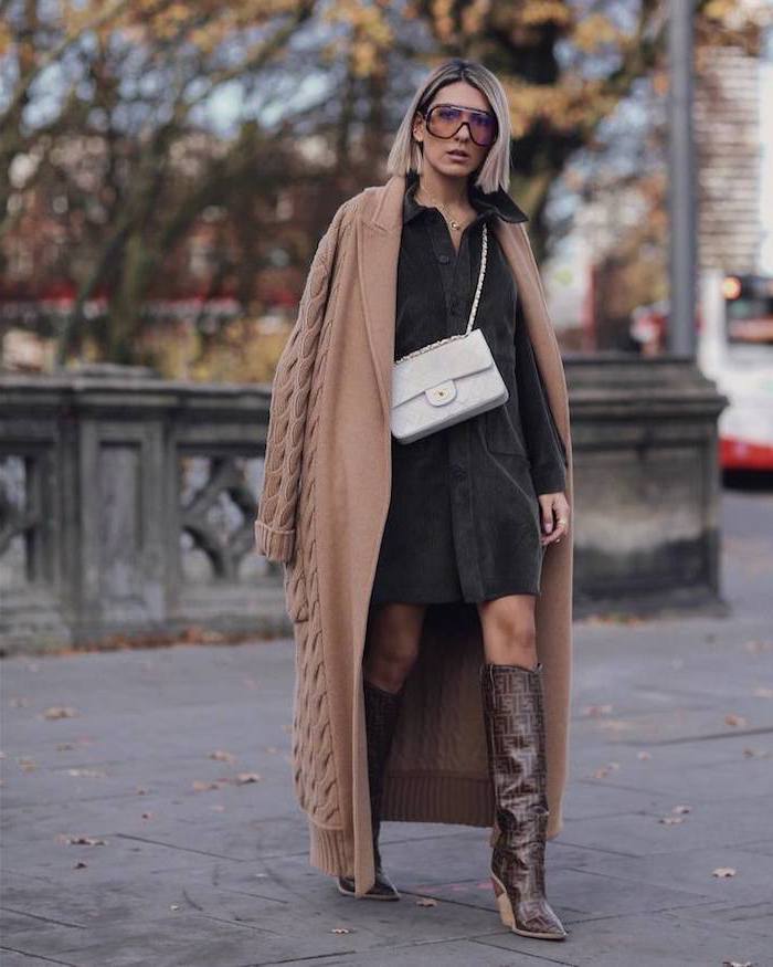 woman wearing black dress, long beige cardigan, brown leather boots, new york winter fashion, white bag