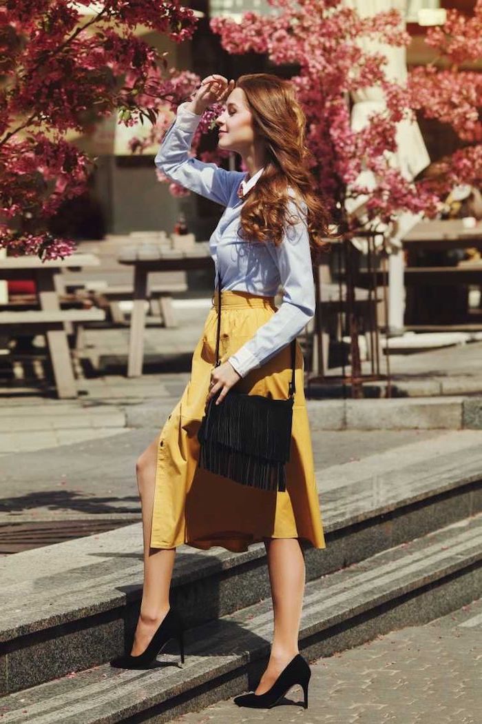 woman with brown wavy hair, wearing blue shirt and yellow skirt, new york winter fashion, black heels and bag