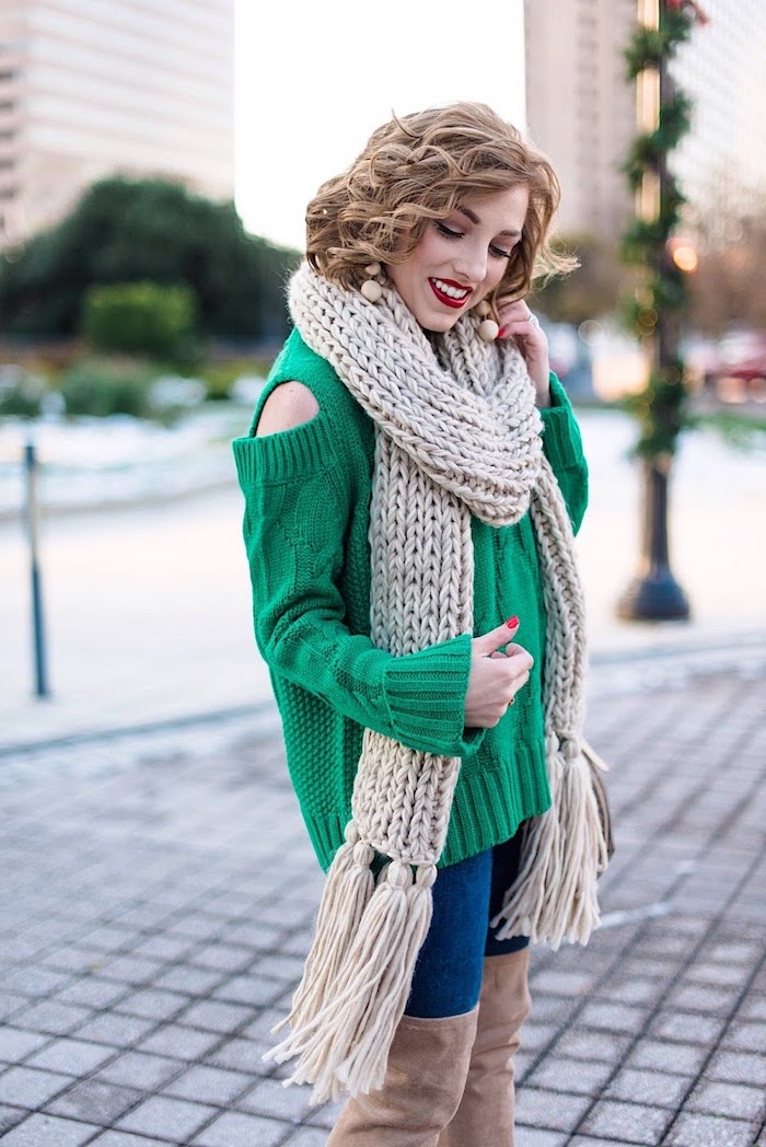 woman wearing green sweater, jeans and knee high boots, best christmas gifts for mom, large beige knitted scarf