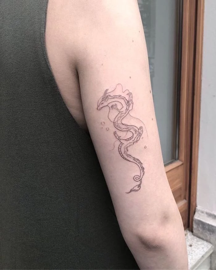back of arm tattoo, woman wearing grey top, dragon thigh tattoo