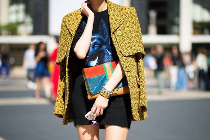 woman on the street, wearing black t shirt dress, yellow coat, fall styles for women, carrying colorful bag