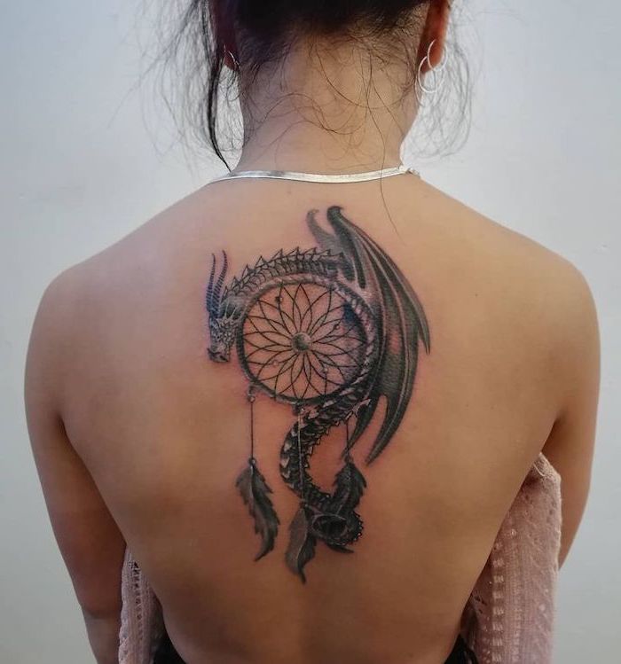 dragon tattoo ideas, back tattoo, large dragon leaning over a dreamcatcher, woman with black hair, wearing silver necklace