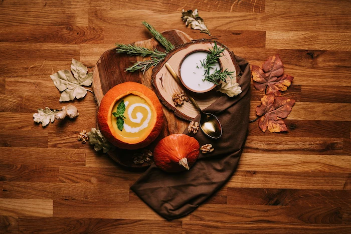 wooden table, fall arrangement on it, cream of chicken soup recipe, pumpkin soup poured inside a carved pumpkin