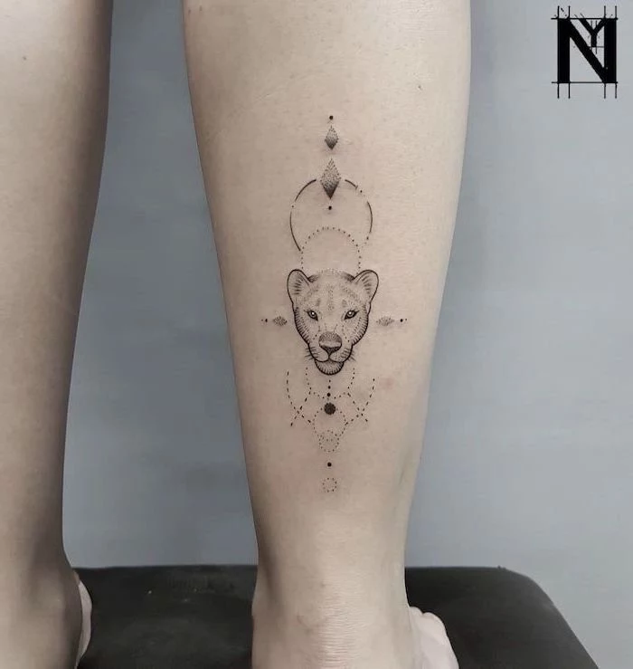 lioness head with geometrical design, lion with crown tattoo, back of leg tattoo, grey background