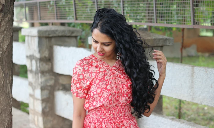 woman with long curly black hair, hair color trends 2020, woman wearing red floral dress