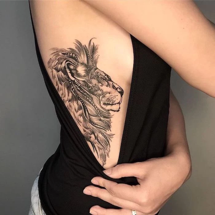 tattoo on the side of the rib cage, lion tattoo, on woman wearing black top, grey background