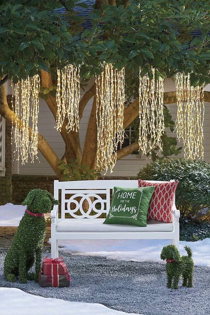 strings of fairy lights, hanging from tree, front porch christmas decorations, over a wooden bench with throw pillows