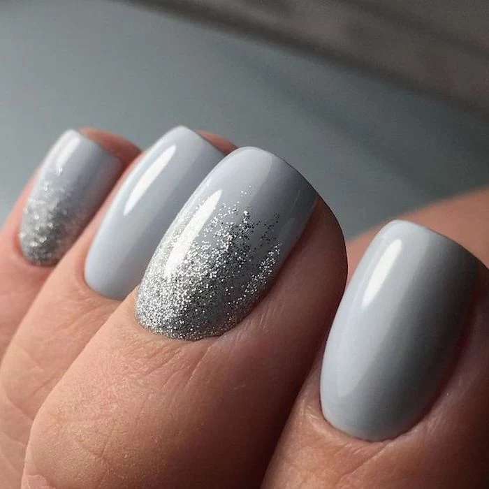 light grey nail polish, winter nail designs, silver glitter on pinky and middle finger, short squoval nails