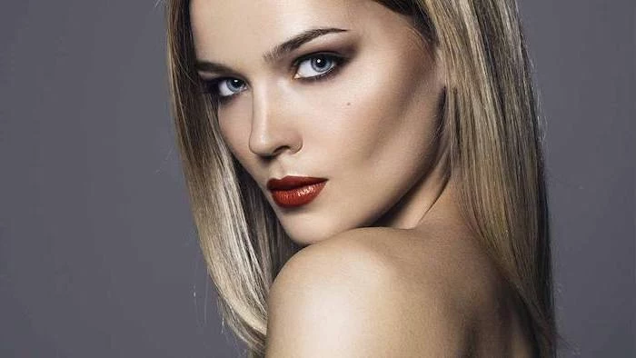 woman with blonde hair, dark red lipstick, brunette highlights, long straight hair, grey background