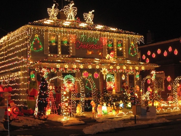 two storey house, decorated with lots of lights, front door christmas decor, lots of lighted figurines in the front yard