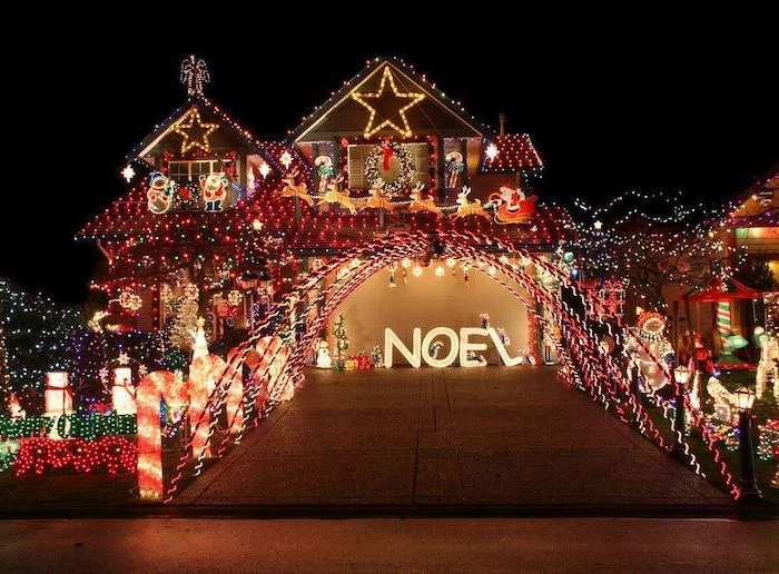 two storey house decorated with lights, front door christmas decor, lots of lighted figurines in the front yard, along the pathway