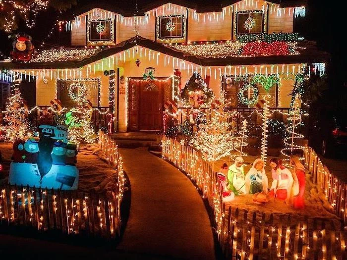 large two storey house, covered with lights, lots of lighted figurines int he front yard, front door christmas decor