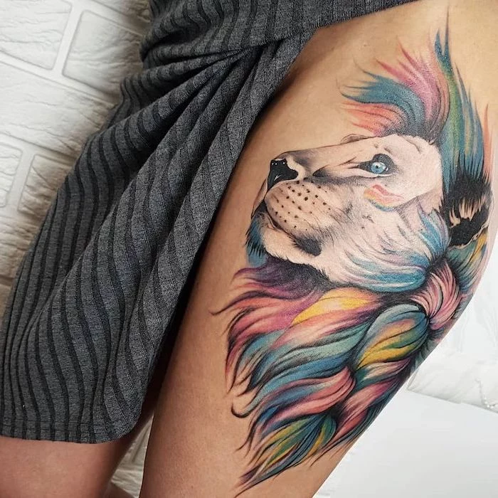 thigh tattoo on woman wearing grey knitted dress, profile of a lion head with colorful mane, lion king tattoo, watercolor tattoo