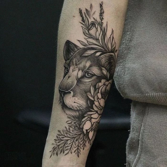 forearm tattoo, lioness head surrounded by flowers, lion hand tattoo, on woman wearing grey blouse