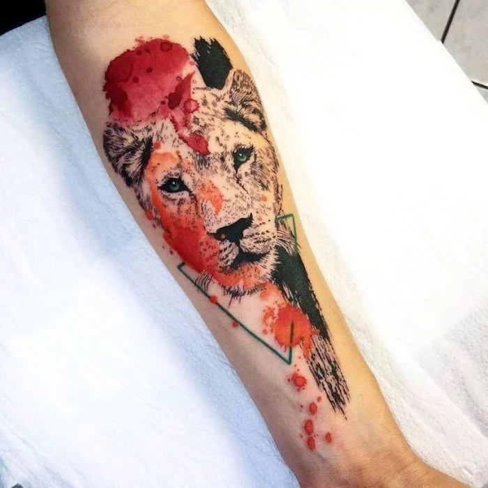 watercolor tattoo, forearm tattoo, lion tattoo on arm, lioness head with red orange and black brush strokes