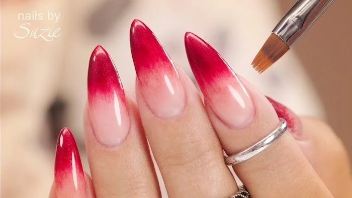 nude to red gradient nail polish, long stiletto nails, pink ombre nails, rings on the index and middle finger