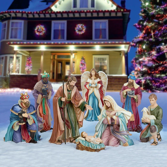 outdoor lighted nativity scene, placed in the snow, in front of a large two storey house, decorated with lights