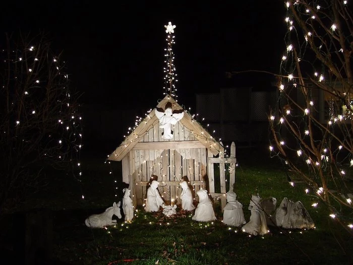 christmas deer decorations, nativity scene made of wood and ceramics, covered with lights, placed in a yard