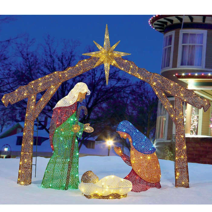 nativity scene with fairy lights, placed in the snow, in front of a house, decorated with lights, christmas deer decorations